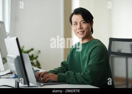 Portrait of smiling software developer working on computer and smiling at camera Stock Photo