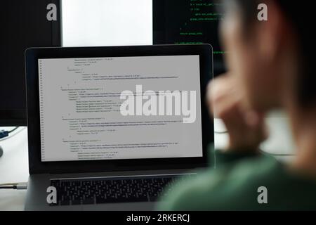 Devops engineer looking at programming code on laptop and computer screens Stock Photo