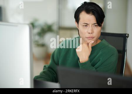 Developer looking at laptop screen with programming code Stock Photo