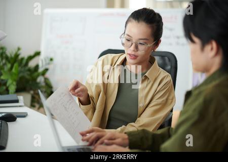 UI designer showing sketch of wireframe to front end developer Stock Photo