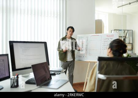 UI designer showing website wireframe and explaining his ideas to developer in meeting Stock Photo