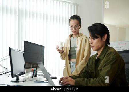 Developers discussing ways to fix bugs in programming code Stock Photo