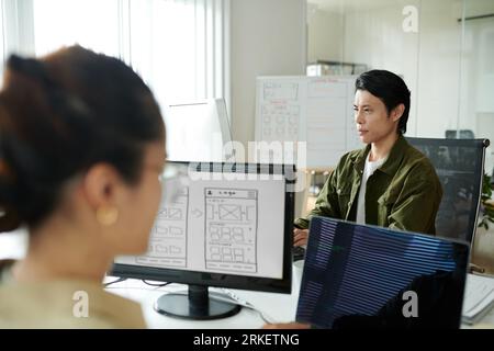 Serious team leader reviewing programming code of junior coworker Stock Photo