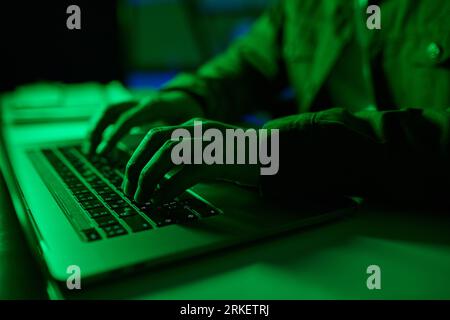Closeup image of developer coding on laptop in green neon light Stock Photo