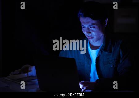 Software developer working in office late at night trying to handle work deadlines Stock Photo