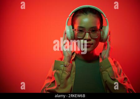 Portrait of young female gamer putting on headphones when getting ready for raid Stock Photo