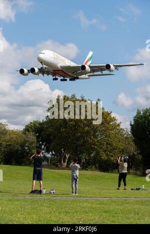 Emirates Airbus A380 jet airliner plane A6-EVN on finals to land at London Heathrow Airport, UK, over enthusiasts in Myrtle Avenue park green space Stock Photo