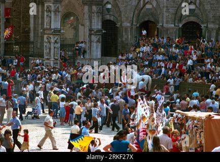 Siena Italy Tourists and Locals watching the Palio di Siena a Horse Raceheld twice a year at the Piazza Del Campo each Jockey Represents one of the Te Stock Photo