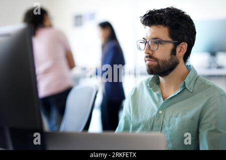 Close-up of bearded businessman using desktop computer while coworkers working in background at office Stock Photo
