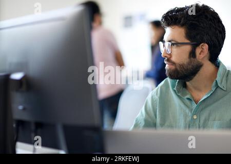 Close-up of bearded businessman using desktop computer while colleagues working in background at office Stock Photo