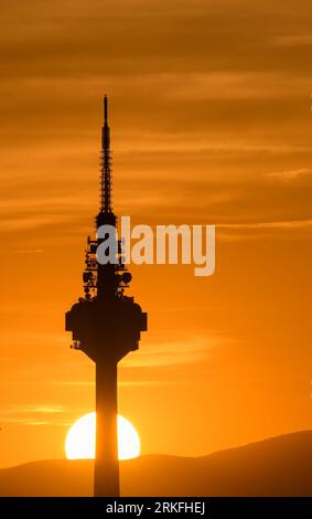 Sunset with the sun setting behind the base of a communications tower. Stock Photo