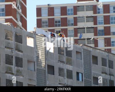 The two workers working on the roof of a new building in a constrcution site Stock Photo