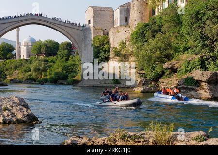 Speed boats on River Neretva and Stari Most (Old Bridge) with the Koski-Mehmed Pasha Mosque behind in Mostar, Bosnia and Herzegovina, August 20, 2023. Stock Photo