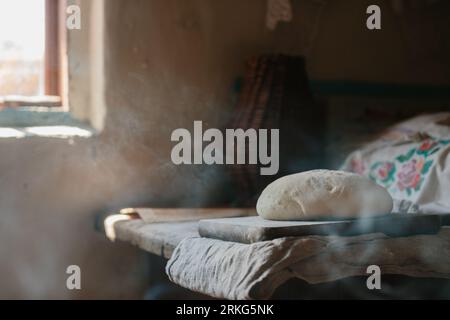 Raw loaf of bread on a wooden table. Stock Photo