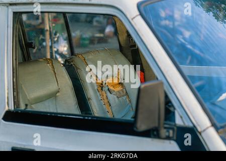 Old dirty car seat beige color of perforated leather with cracks and scuffs in the workshop for repair and restoration of vehicle interiors. Leatheret Stock Photo