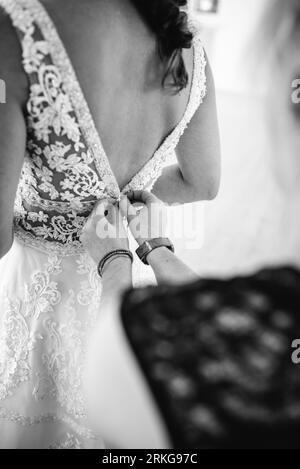 A female figure seen from behind dressed in a white bridal gown, with the fabric trailing to the ground Stock Photo