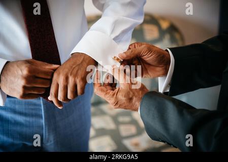 Two men standing side by side in suits, adjusting their cuffs a gesture of camaraderie Stock Photo
