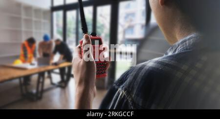 Asian male supervisor engineer standing at construction site and communicating with walkie talkie and worker engineers working background Stock Photo