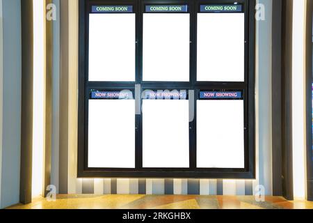 In the theater walkway, an empty billboard cinema poster panel stands ready, a white blank mockup movie frame with "Coming Soon" text, inviting your d Stock Photo