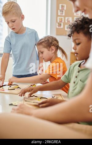 multiethnic kids and teacher using didactic materials during lesson in montessori school Stock Photo