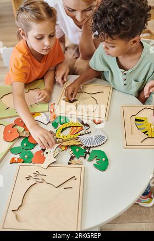 high angle view of multiethnic kids playing near teacher during lesson in montessori school Stock Photo