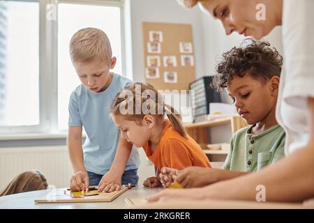 teacher and multiethnic kids playing with didactic materials in montessori school Stock Photo
