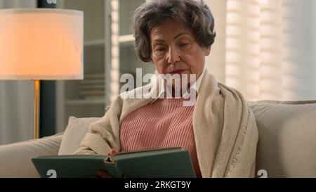 Serious dissatisfied Caucasian old woman senior mature lady covered with blanket calm elderly female retired middle-aged granny grandmother at home Stock Photo