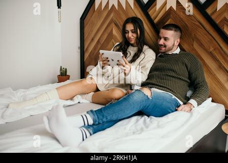 An intimate moment between a couple sitting on a bed with paperwork in their hands Stock Photo