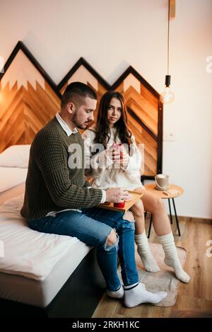 A young couple relaxing in bed drinking coffee and enjoying a moment together Stock Photo