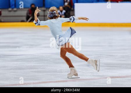 figure skating single, rear view girl figure skater in blue dress Stock Photo