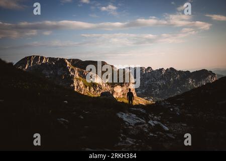 A young man striding through a mountainous landscape Stock Photo