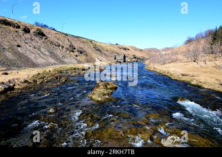 Fast flowing river running through Hveragerdi in rural and remote Iceland. Stock Photo