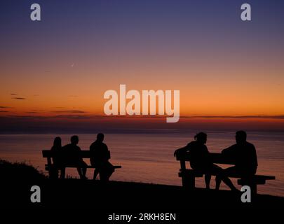 Idyllic sunset on the French coast, magenta, orange and blue colors in the sky while in the foreground you can see the silhouette of some people in th Stock Photo