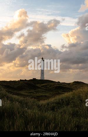 An idyllic scene of a majestic lighthouse perched atop a grassy hill overlooking the ocean Stock Photo