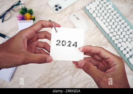 Male hand holding table calendar with white marble background. To-do list and plans for 2024 Goals for next year. Stock Photo