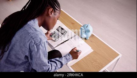Young African Woman Calculating Invoice With Calculator Stock Photo