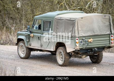 A medium size four-wheeled military utility vehicle is driving along a rugged mud track in Wilts, United Kingdom, during a military exercise Stock Photo