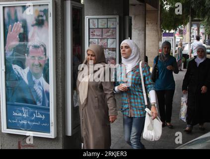 Bildnummer: 56130006  Datum: 27.09.2011  Copyright: imago/Xinhua (110927) -- DAMASCUS, Sept. 27, 2011 (Xinhua) -- Syrians walk by a large picture of Syrian President Bashar al-Assad in Damascus, Syria, on Sept. 27, 2011. The European Union agreed on Saturday to impose sanctions on six Syrian companies, including Syriatel and its largest private company, Cham Holding, to intensify pressure on President Bashar al-Assad, who has come under withering international criticism for his regime s months-long crackdown on protests. (Xinhua/Bassim) SYRIA-POLITICS-PRESIDENT PUBLICATIONxNOTxINxCHN People Po Stock Photo