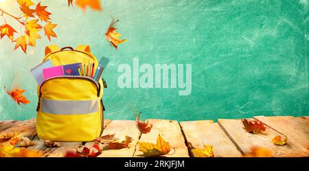 Schoolbag On Table With Stationary And Leaves - Backpack For Back To School Concept Stock Photo