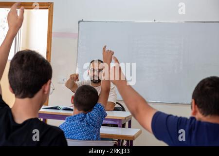 Students raising their hands to answer the teacher question Stock Photo