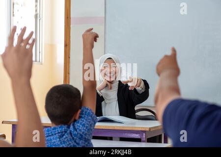 Students raising their hands to answer the teacher question Stock Photo