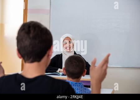 Students raising their hands to answer the teacher question Stock Photo