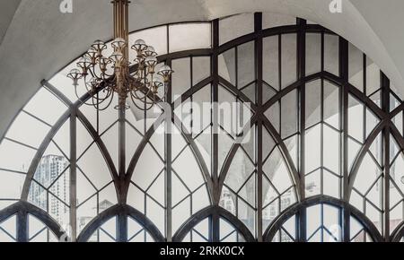 Bangkok, Thailand - Jul 28, 2023 - Chandelier (Chanderia) is hung on the roof, which is in the hall. The wall is decorated with ancient glass wall bac Stock Photo