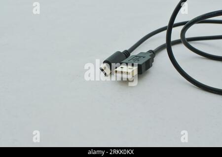 Black USB Type-C cable detail highlighted on a clear surface, perfect for modern technology concepts. Close-up black USB Type-C cable providing speed Stock Photo