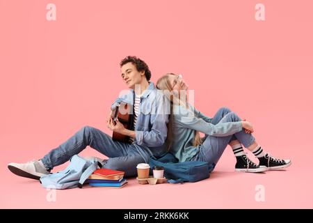 Teenage girl with her boyfriend playing guitar on pink background Stock Photo