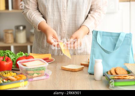 Mother making sandwiches for school lunch on table at kitchen Stock Photo