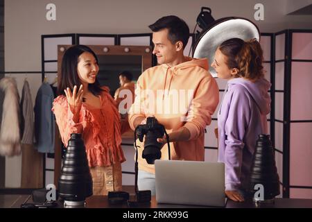 Male photographer and his assistant working with Asian model in studio Stock Photo