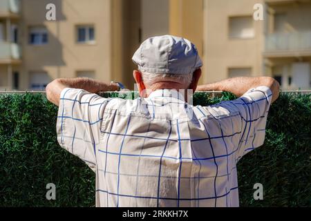a mature man standing and talking with the neighbors on the terrace of his house. rear view Stock Photo