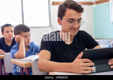 Teenager using the tablet in school and have a smile on his face Stock Photo