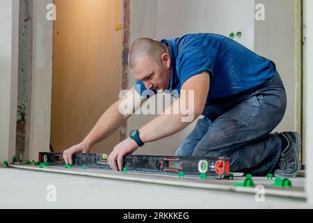Tiler placing ceramic wall tile in position over adhesive with lash tile leveling system. Ceramic Tiles Stock Photo
